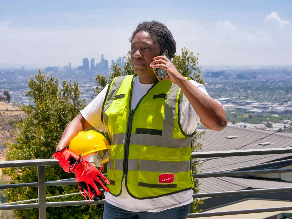 A colleague in high-visibility clothing taking a phone call at a stationary outdoor worksite.